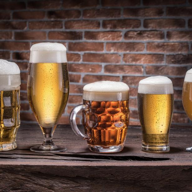 Eine Auswahl verschiedener Biersorten in unterschiedlichen Gläsern auf einem Holztisch.