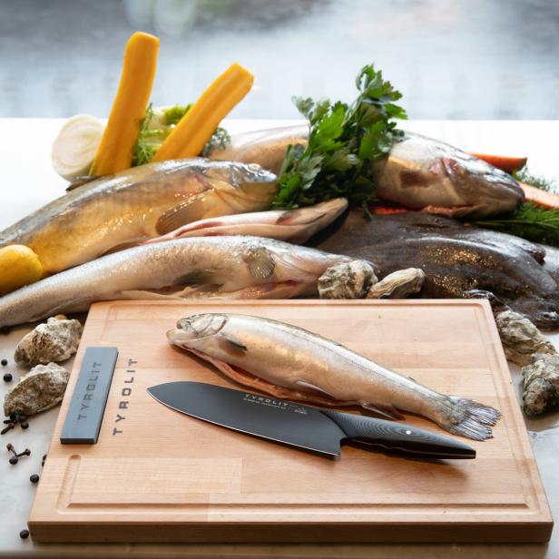 Verschiedene Fische, Gemüse und Kräuter liegen auf einem Tisch.