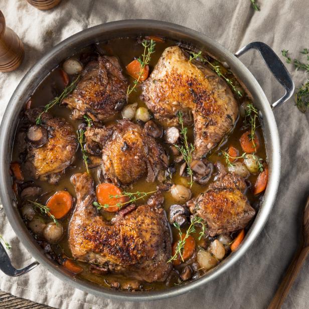 Coq au Vin, ein französisches Gericht mit Huhn, Gemüse und Rotwein, in einer Pfanne.