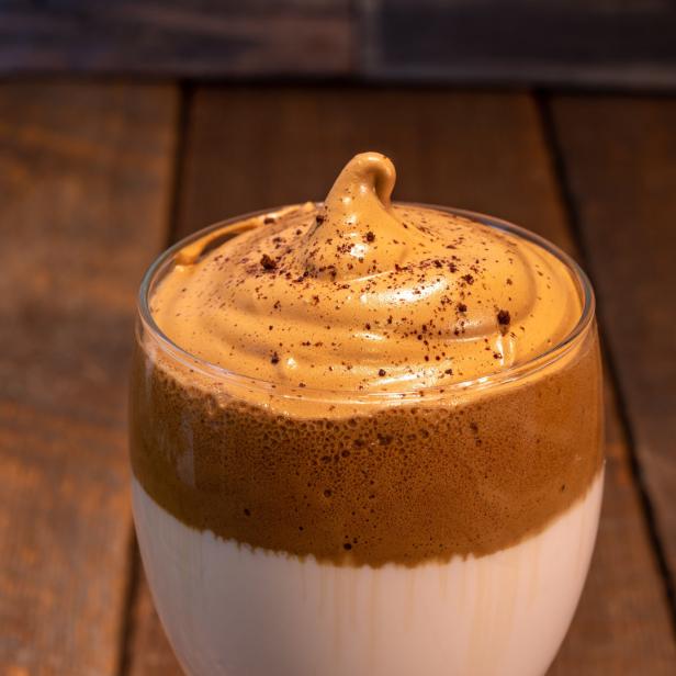 Ein Glas Dalgona-Kaffee mit einem Klecks Kaffeepulver oben drauf.