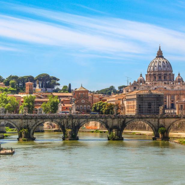 Die Engelsbrücke führt über den Tiber zur Vatikanstadt mit dem Petersdom im Hintergrund.