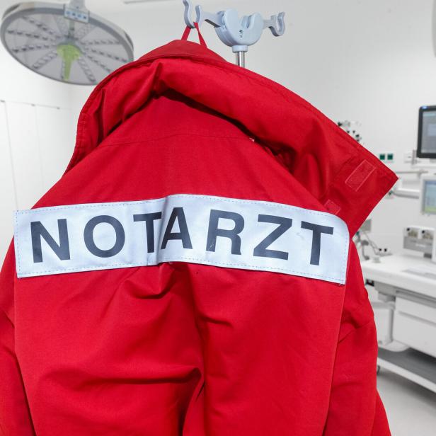 Die rote Jacke eines Notarztes hängt in einem Behandlungsraum.