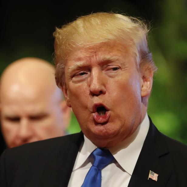 Donald Trump steht mit offenem Mund im schwarzen Sakko und blauer Krawatte vor der Kamera.