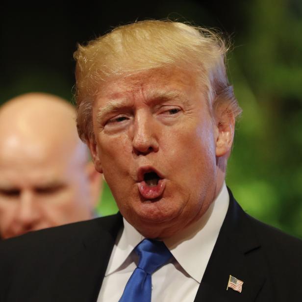 Donald Trump steht mit offenem Mund im schwarzen Sakko und blauer Krawatte vor der Kamera.