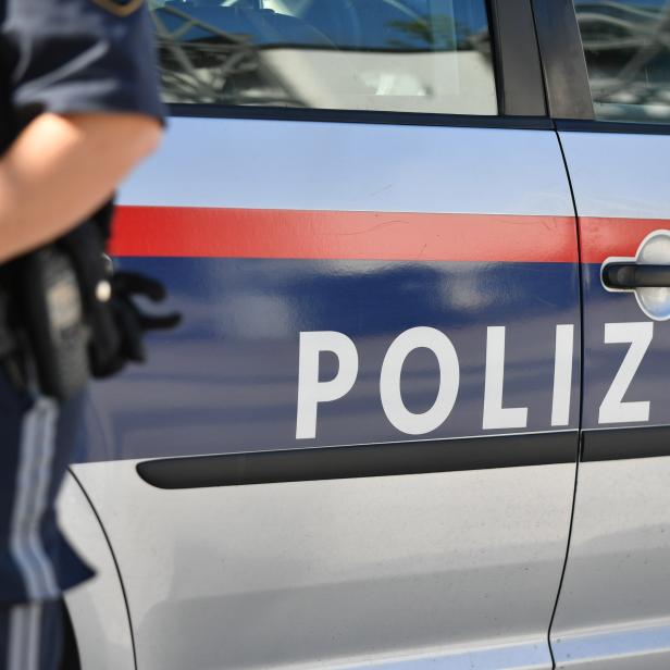 Ein Beamter geht links aus dem Bild - hinter ihm ist das Polizeiauto im Fokus.