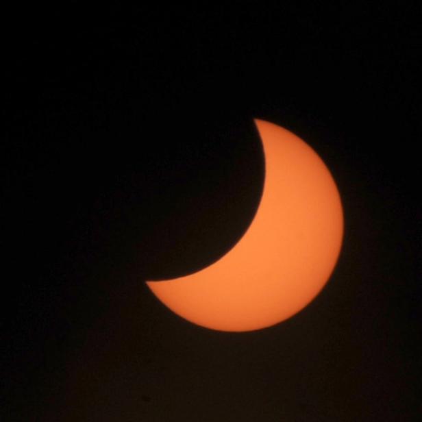 Eine partielle Sonnenfinsternis vor einem dunklen Himmel.