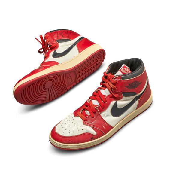 Zwei rote und weiße Nike Air Jordan 1 High-Top-Sneakers auf einem weißen Hintergrund.