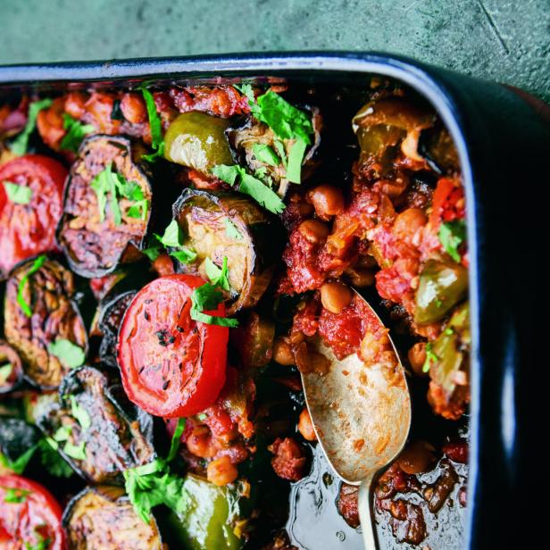 Ein Gericht mit gebratenen Auberginen, Tomaten, Paprika und Kichererbsen in einer schwarzen Pfanne.