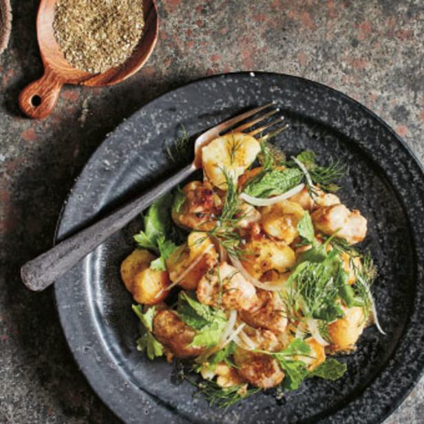 Ein Teller mit Kartoffelsalat, garniert mit frischen Kräutern und Zwiebeln.