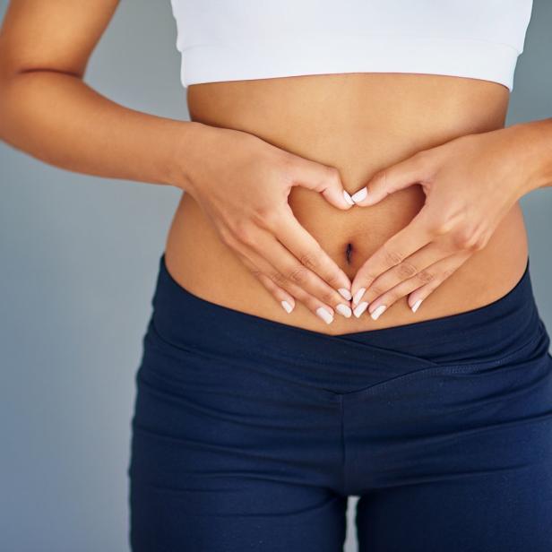Eine Frau formt mit ihren Händen ein Herz über ihrem Bauch.