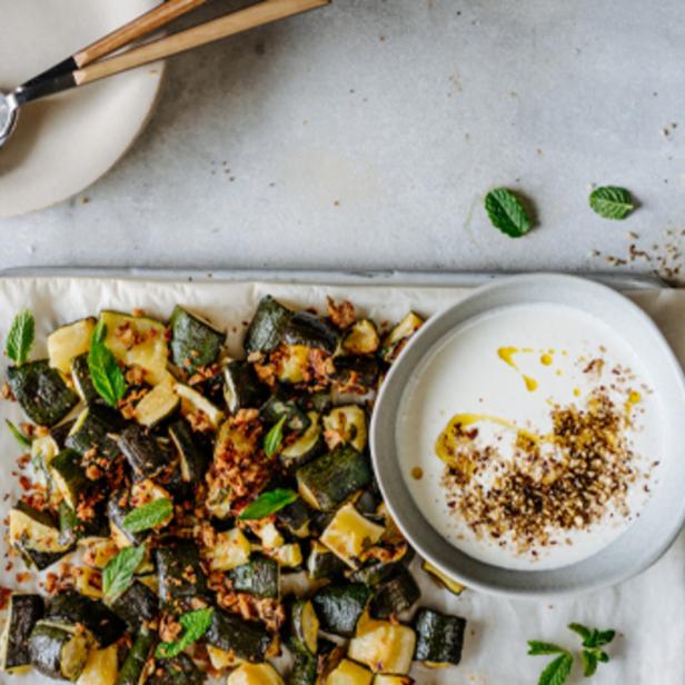 Geröstete Zucchini mit Joghurt und Minze auf einem Backblech angerichtet.
