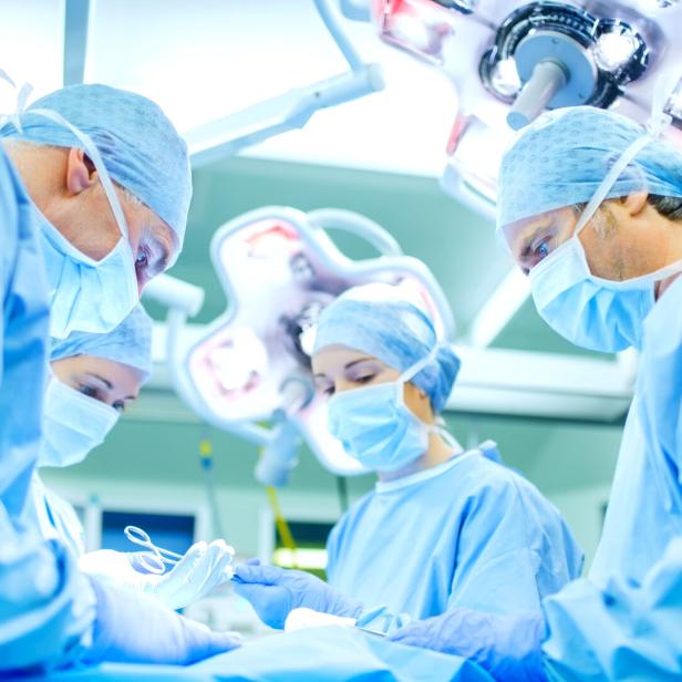 Surgeons Performing Surgery On Patient In Operating Room