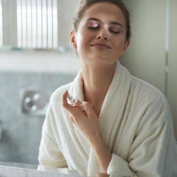 Frau sprüht sich mit Parfum ein.
