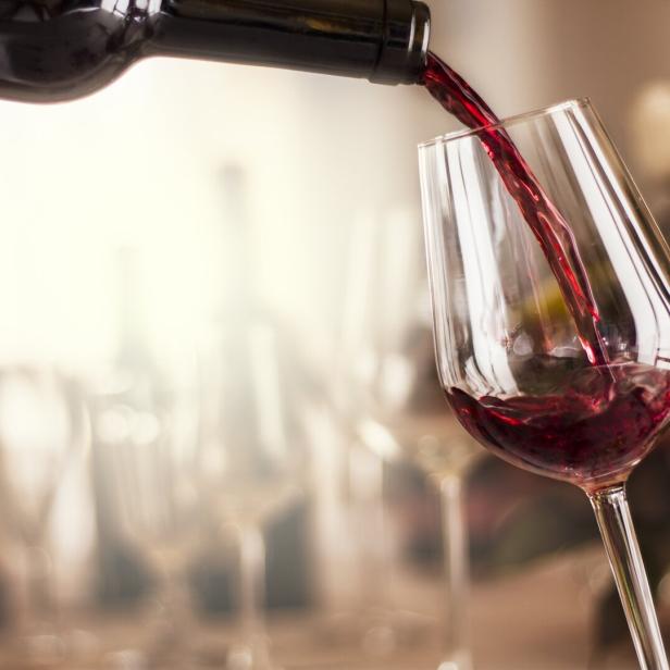 Rotwein wird in ein Weinglas gegossen.