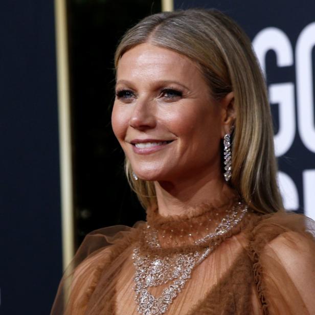 Gwyneth Paltrow auf dem roten Teppich mit einem braunen Kleid und auffälligem Schmuck.