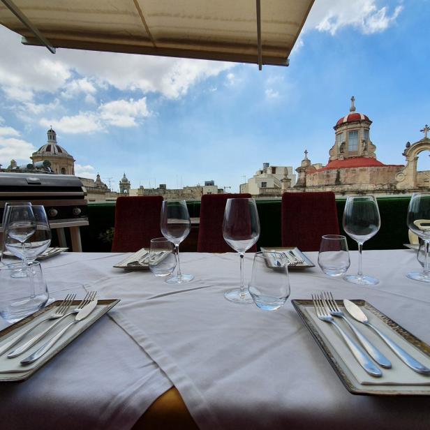 Ein gedeckter Tisch auf einer Dachterrasse mit Blick auf historische Gebäude.