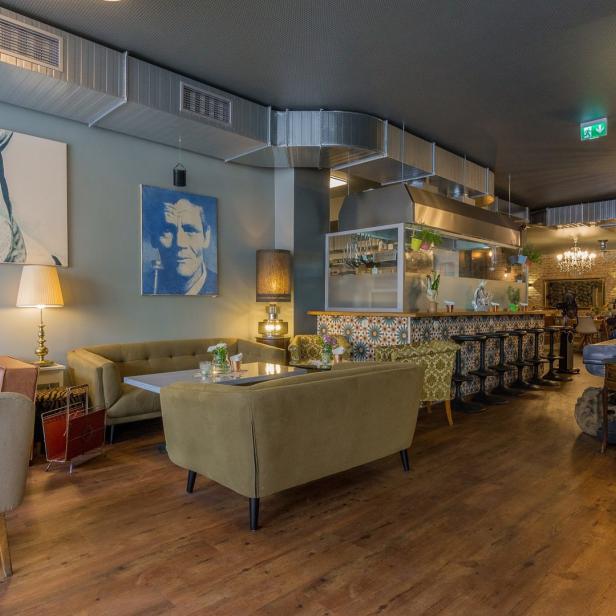 Innenansicht eines Cafés mit Sofas, Sesseln und einer Bar.