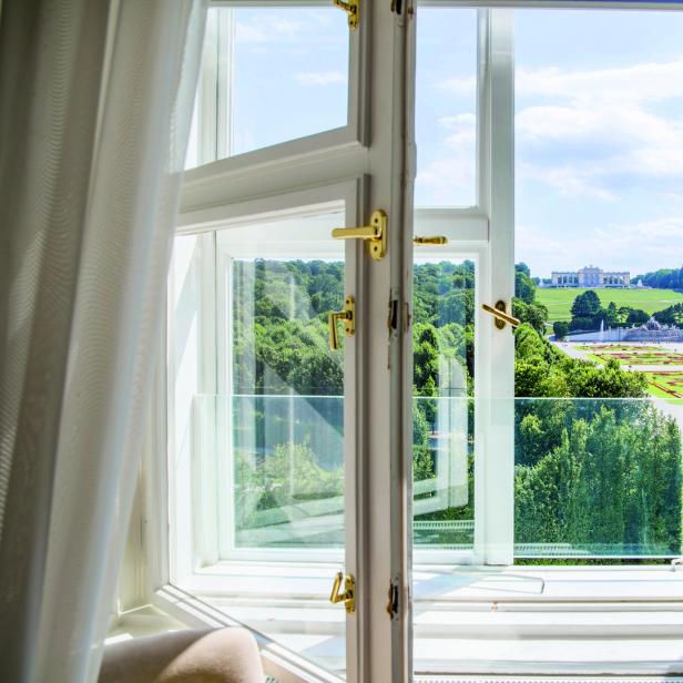 Blick aus einem Fenster auf Schloss Schönbrunn und den Garten in Wien.