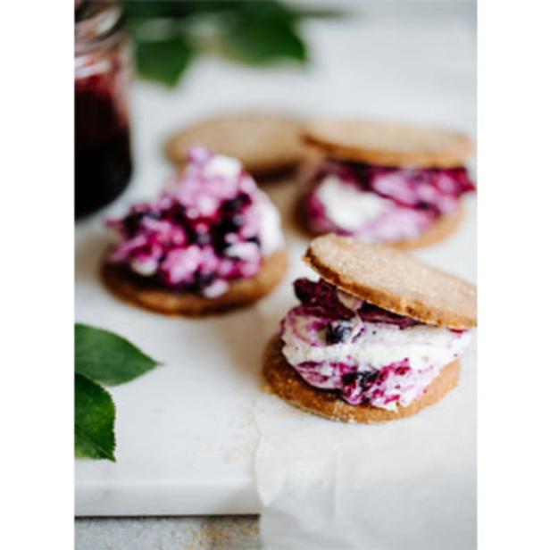 Drei Blaubeer-Sandwich-Kekse auf einem weißen Teller.