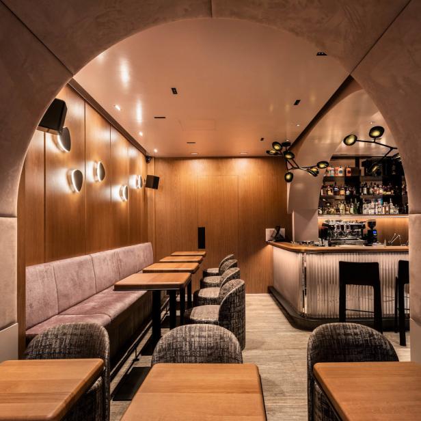 Innenansicht einer Bar mit Tischen, einer Sitzbank und einer Bar im Hintergrund.