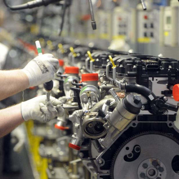 Ein Arbeiter montiert in einer Fabrik einen Motor an der Produktionslinie.
