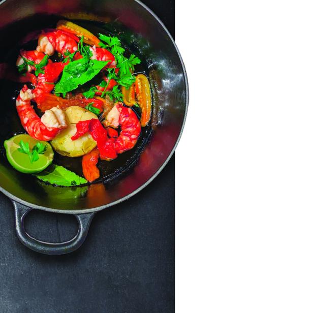 Gebratene Garnelen mit Kräutern, Knoblauch und Limette in einer Pfanne.
