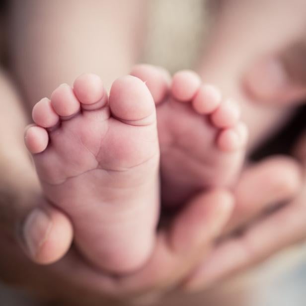 Eltern halten die Füße ihres Neugeborenen.