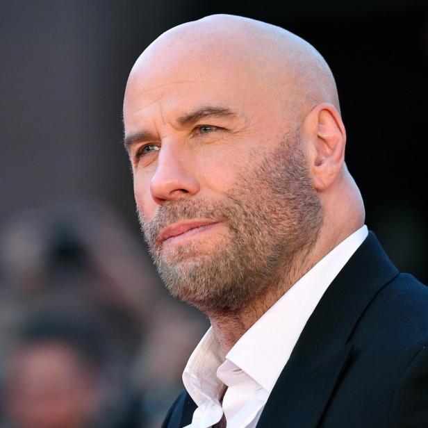 Porträt von John Travolta mit Bart und Anzug.