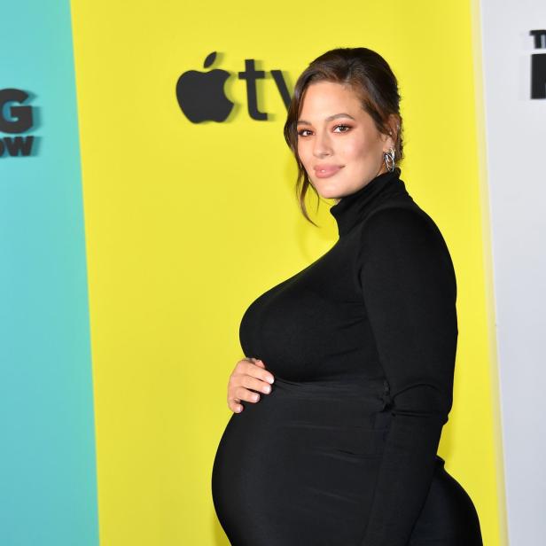 Die schwangere Ashley Graham posiert vor Werbeplakaten für „The Morning Show“.