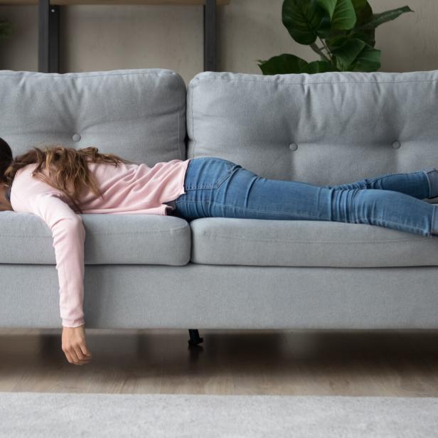 Frau liegt auf dem Bauch auf einer Couch.