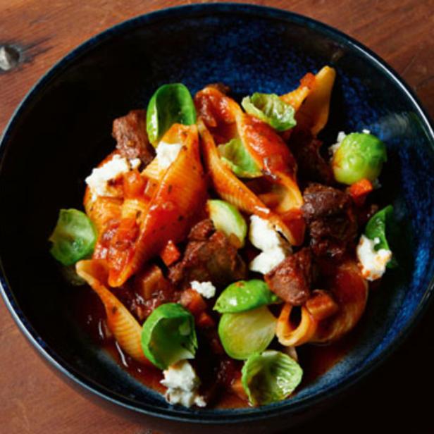 Eine Schüssel mit gefüllten Muschelnudeln, Fleisch und Rosenkohl in Tomatensoße.