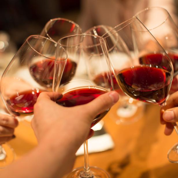 Gläser mit Rotwein stoßen an.
