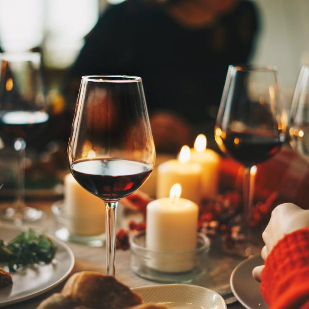 Ein festliches Abendessen mit Rotwein und Kerzenlicht auf dem Tisch.
