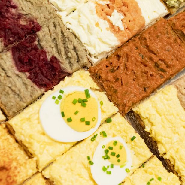 Verschiedene Canapés, belegt mit Wurst, Käse und Ei, auf einem Tablett.
