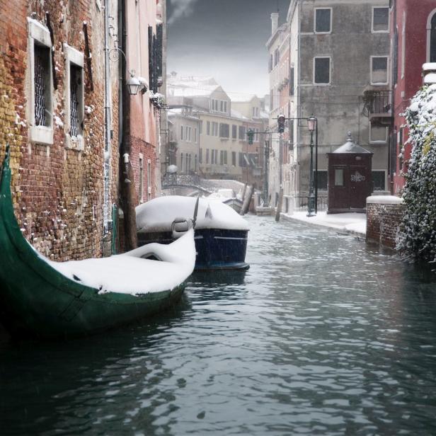 Eine verschneite Gondel liegt in einem Kanal in Venedig.