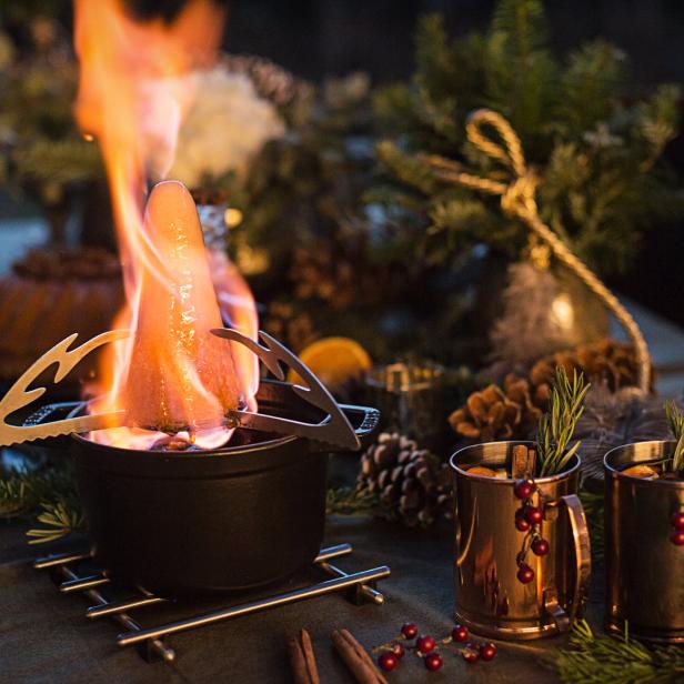 Eine Feuerzangenbowle wird über einer offenen Flamme zubereitet.