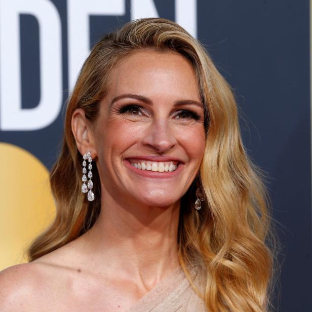 Julia Roberts lächelt mit Diamantohrringen auf dem roten Teppich.