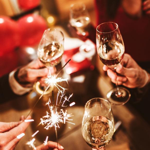 Menschen feiern Silvester mit Sekt und Wunderkerzen.