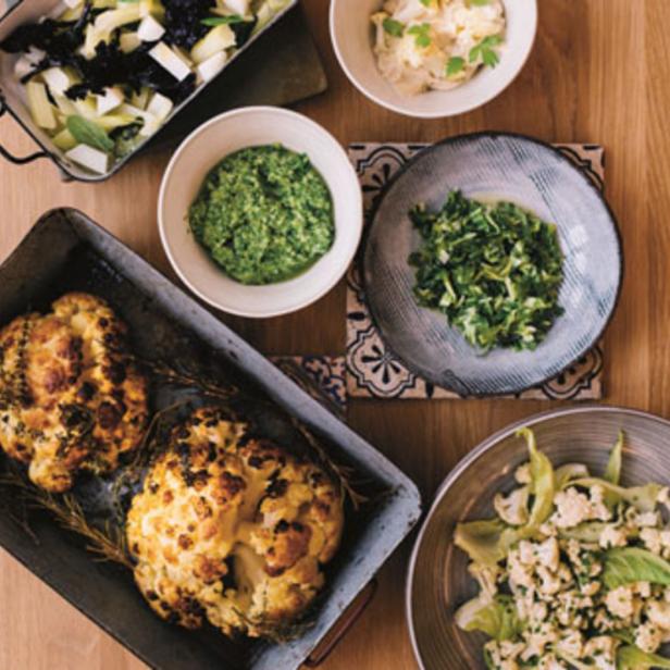 Verschiedene Gerichte mit Gemüse, darunter Blumenkohl, Pesto und Salate, sind auf einem Tisch angerichtet.