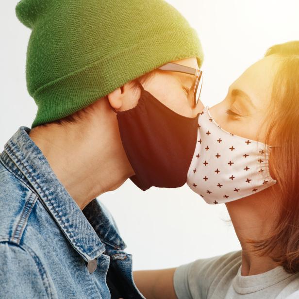 Ein Paar küsst sich mit Gesichtsmasken.
