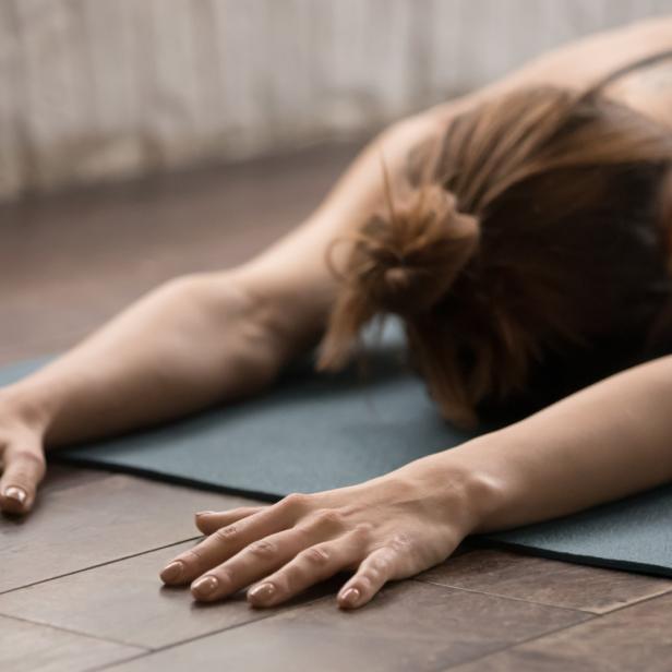 Eine Frau dehnt sich auf einer Yogamatte in der Kindhaltung.