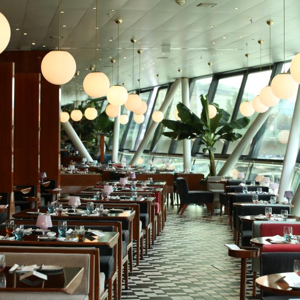 Ein elegantes Restaurant mit gedeckten Tischen und großen Fenstern.