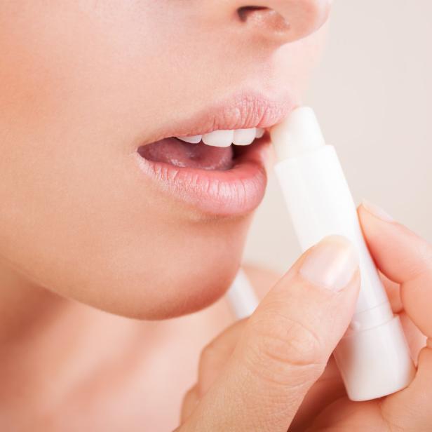 Eine Frau trägt Lippenbalsam auf ihre Lippen auf.