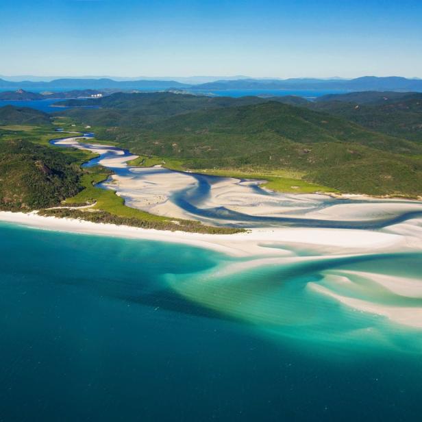 Luftaufnahme von Whitsunday Island mit türkisfarbenem Wasser und weißem Sand.