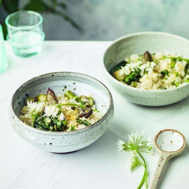 Zwei Schalen mit Risotto, Bärlauch und grünem Spargel auf einem Tisch.
