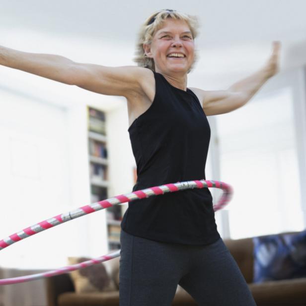 Frau hat Spaß an Bewegung mit Hula Hoop-Reifen.