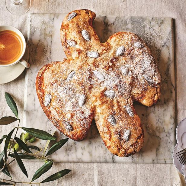 Ein Colomba Pasquale, ein italienischer Osterkuchen in Taubenform, mit Mandeln und Puderzucker auf einem Tisch.