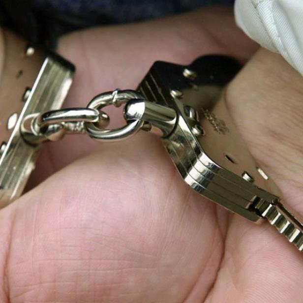 Nahaufnahme von Händen, die mit Handschellen gefesselt sind.