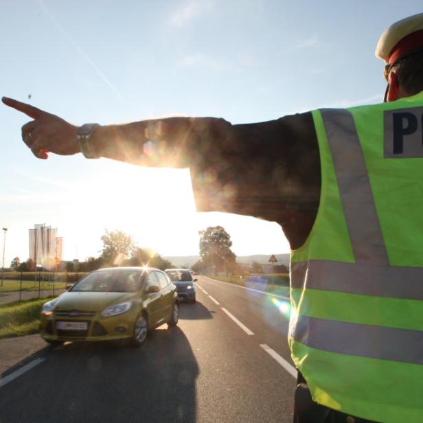 Ein Polizist in Uniform regelt den Verkehr auf einer Landstraße.
