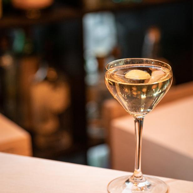 Ein Cocktail mit Zitronenzeste steht auf einer Bar.